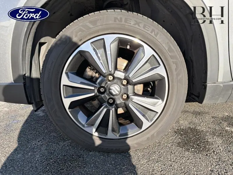 Gros plan sur la jante alu gris foncé du Suzuki Vitara Galactic Gray, mettant en valeur le logo Suzuki central.