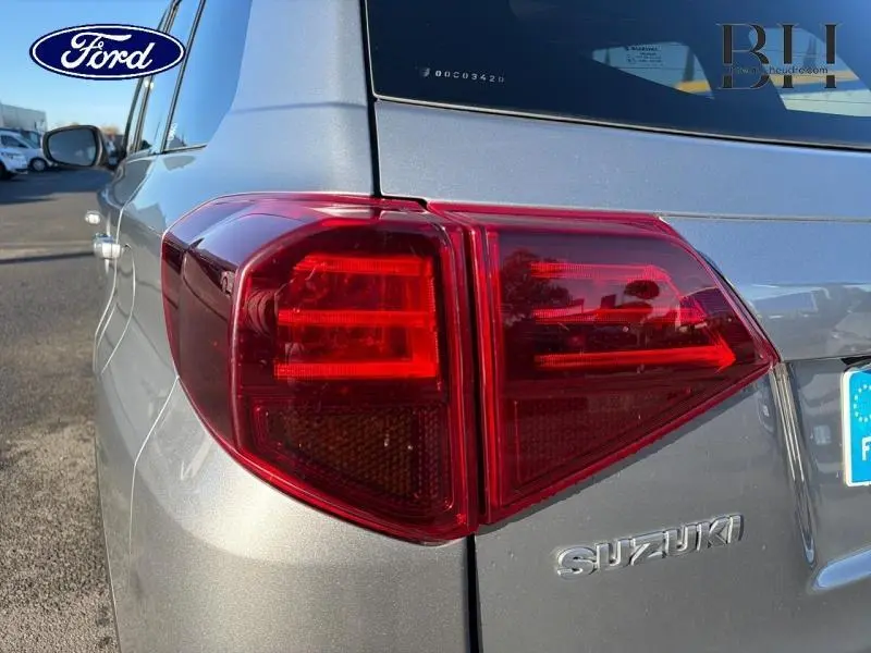 Gros plan sur le feu arrière gauche d’un Suzuki Vitara Galactic Gray métallisé, avec logo Suzuki visible.