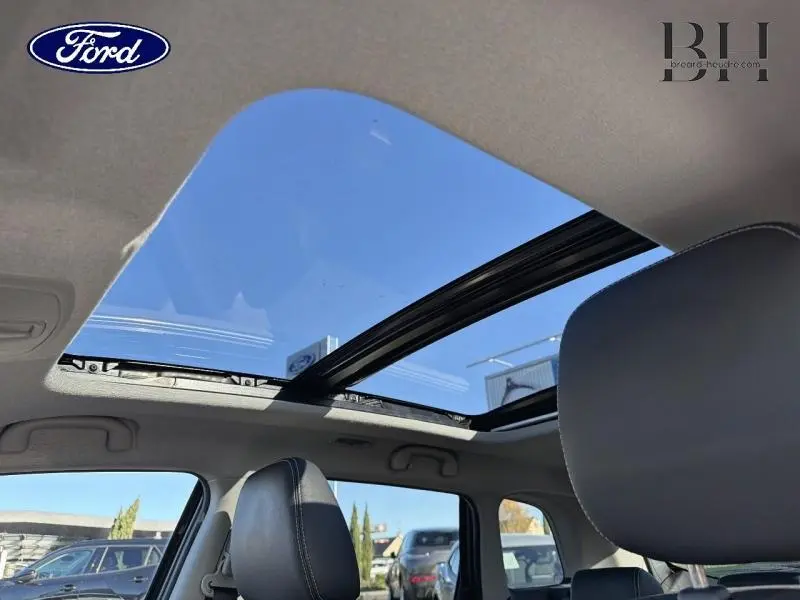 Toit panoramique en verre ouvert vu de l'intérieur sur un Suzuki Vitara Galactic Gray métallisé, sièges en cuir noir visibles.