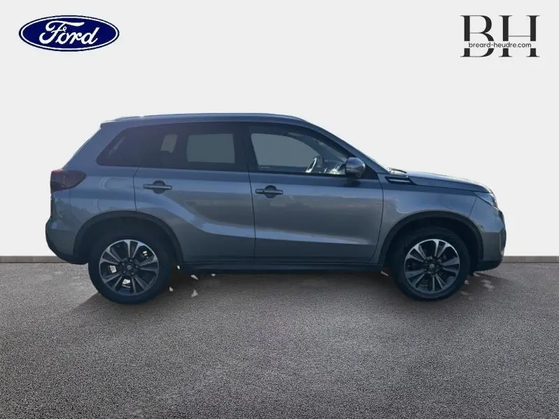 Vue de profil côté gauche du Suzuki Vitara 1.4 Boosterjet Hybrid 2022 en Galactic Gray métallisé avec jantes alu noires.