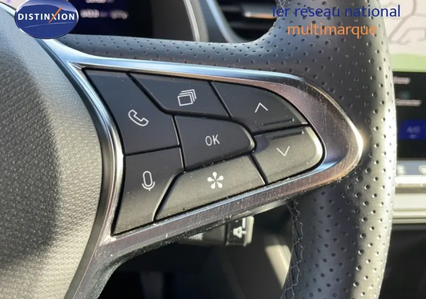 Gros plan sur les commandes multifonctions en plastique noir et chrome du volant perforé côté gauche du Renault Symbioz gris cassiopée.