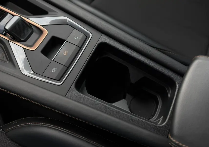 Gros plan sur la console centrale noire avec commandes électroniques et accoudoir en cuir surpiqué marron du CUPRA Formentor.