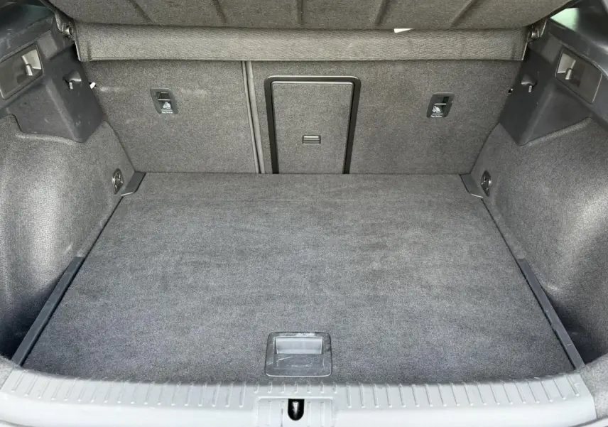 Coffre ouvert du CUPRA Formentor blanc Neige, vue intérieure montrant un espace de chargement propre et bien fini en tissu gris.