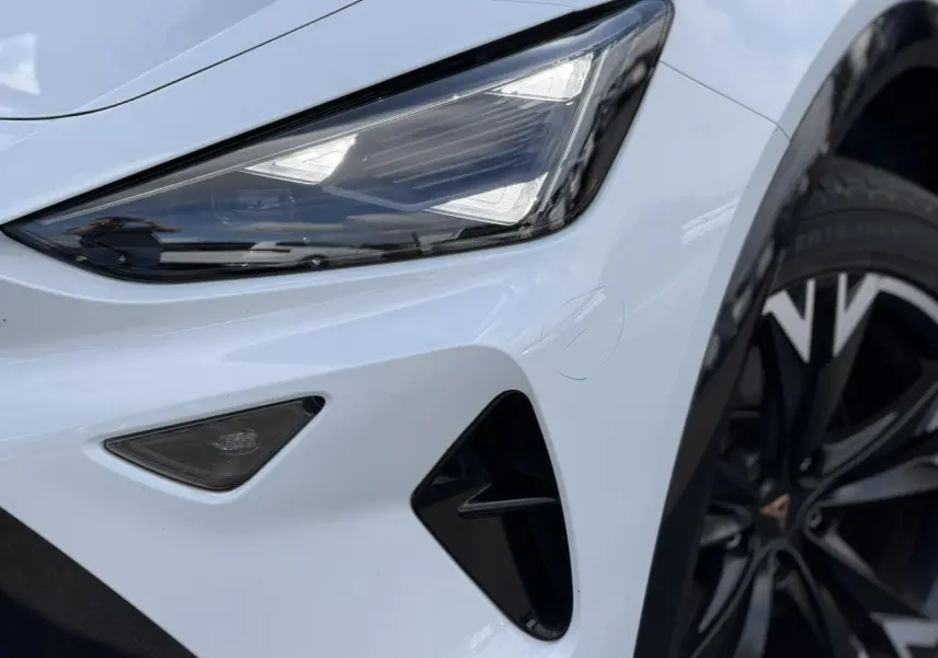 Gros plan sur le phare avant gauche blanc Neige du CUPRA Formentor 2025 avec jante alliage noire et détails noirs contrastants.