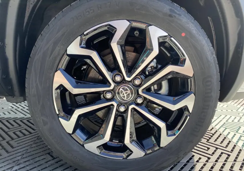 Gros plan sur la jante alliage 17'' bicolore noir et argent du Toyota Yaris Cross blanc pure, avec logo Toyota central.