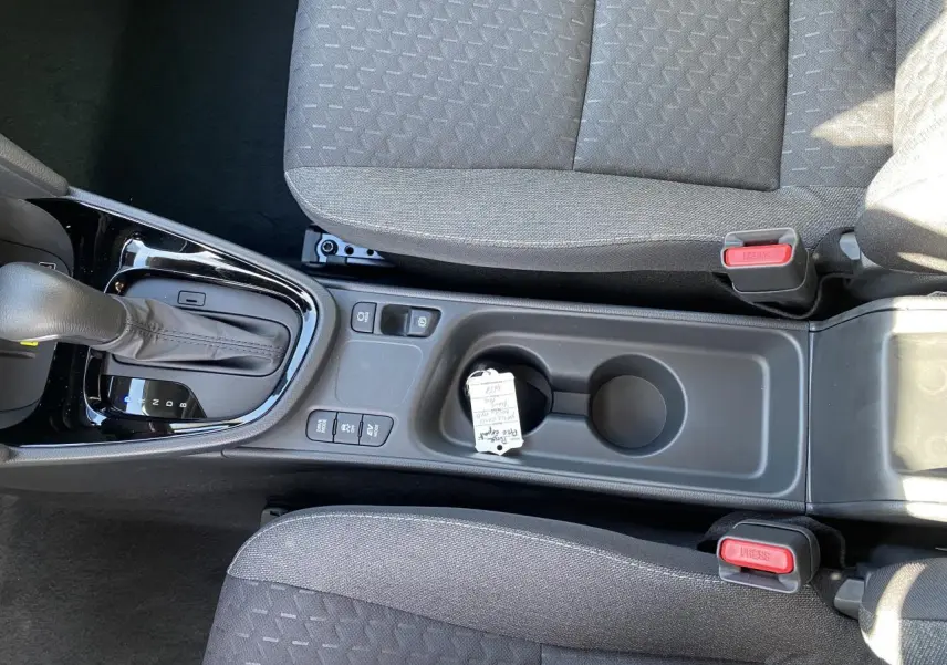 Vue plongeante sur la console centrale et la boîte auto d'une Toyota Yaris Cross blanche, avec sièges tissu gris.