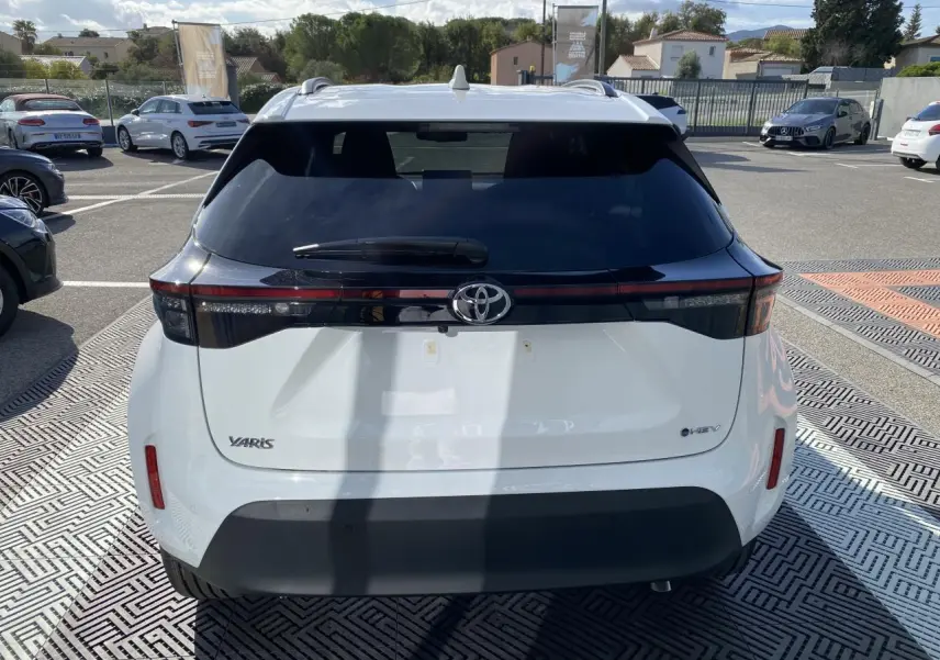 Vue arrière d'une Toyota Yaris Cross blanche avec lunette arrière noire et feux arrière LED horizontaux.