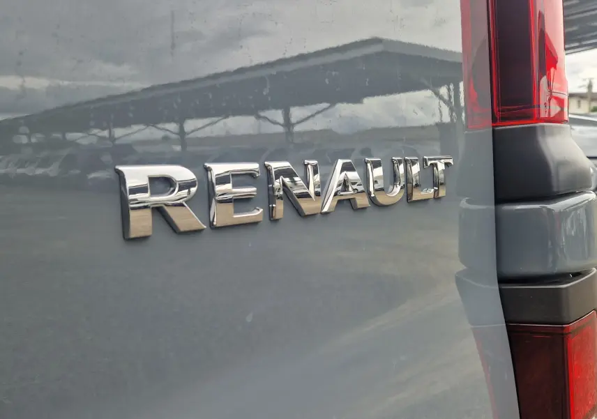 Gros plan sur l'arrière droit gris urbain du Renault Trafic Fourgon 2025 avec logo chromé et feu arrière vertical rouge.