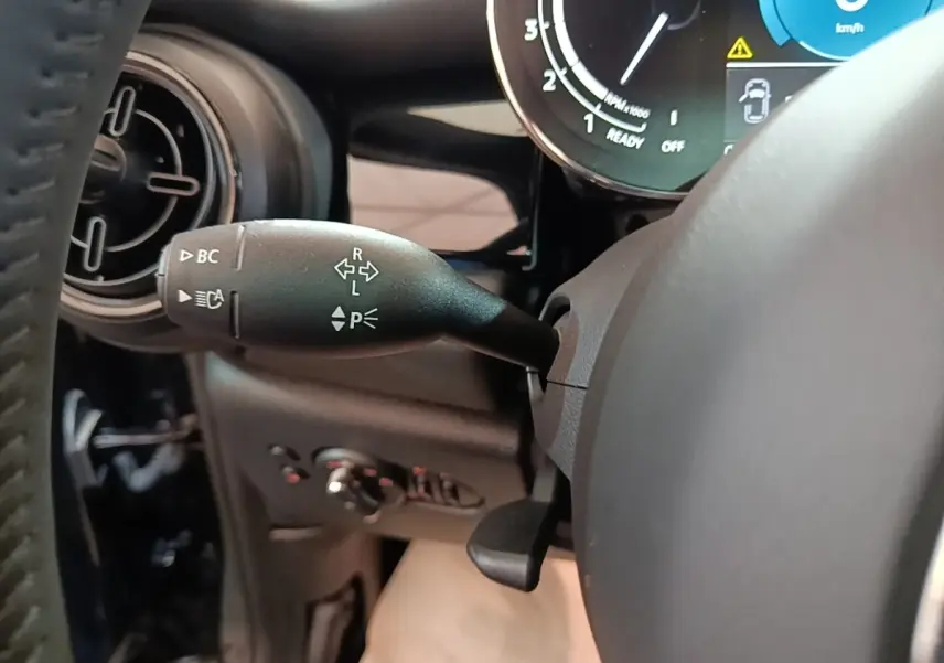 Gros plan sur la manette de clignotant et le combiné d'instruments numérique dans l'habitacle noir d'une MINI Cooper 2023.