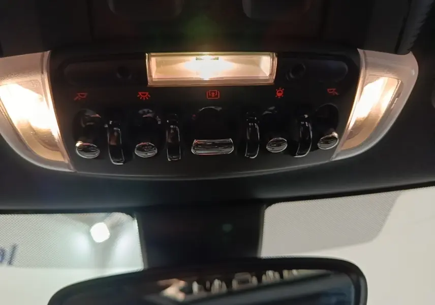 Vue intérieure du panneau de commandes de plafonnier avec interrupteurs chromés et éclairage, MINI Cooper 2023 noir.