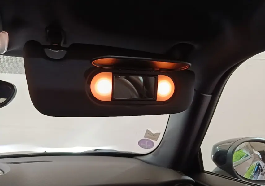 Détail intérieur du pare-soleil avec miroir éclairé dans une MINI Cooper Edition Premium Plus noire, vue côté conducteur.