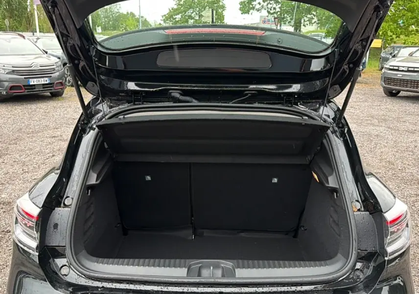 Coffre ouvert vu de l'arrière d'une Renault Clio V noire, montrant l'espace de chargement et les feux arrière LED.