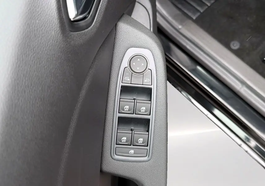 Gros plan sur les commandes des vitres électriques côté gauche d’une Renault Clio V noire, intérieur sombre.