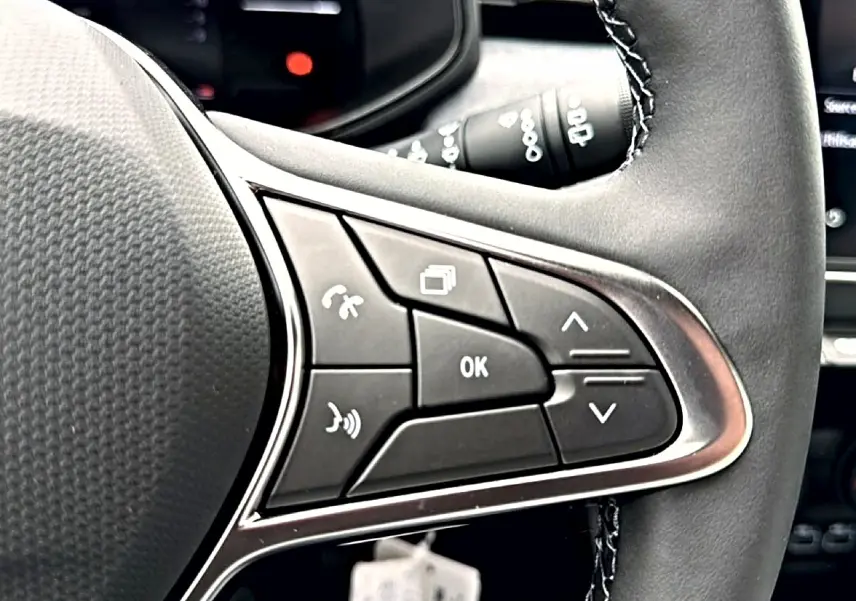 Gros plan sur les commandes multifonctions à droite du volant noir de la Renault Clio V 1.0 TCe 90 Evolution.