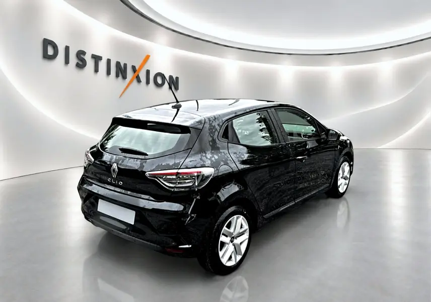 Renault Clio V noire vue en 3/4 arrière droit, avec feux arrière LED et becquet sur fond blanc lumineux.