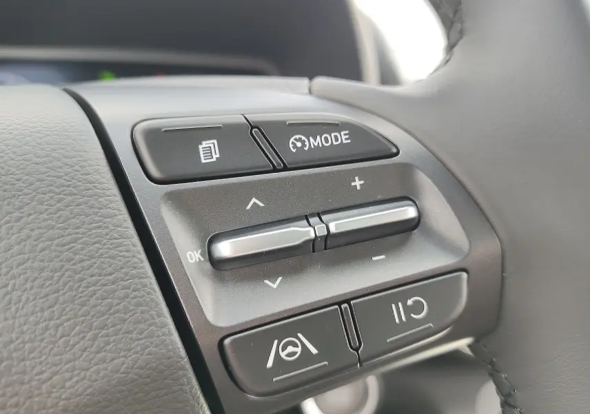 Gros plan sur les commandes de régulateur de vitesse au volant cuir du Hyundai Kona Electric gris métallisé 2025.