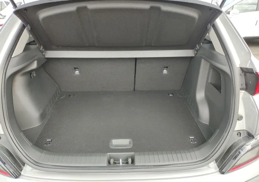 Coffre ouvert d'une Hyundai Kona électrique gris métallisé, vue arrière montrant l'espace de chargement vide.