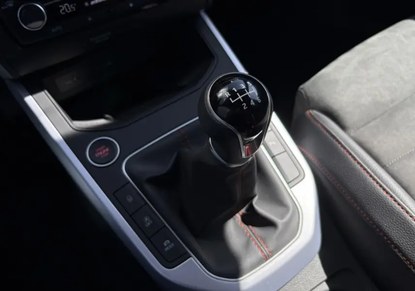 Gros plan sur le levier de vitesse manuel du SEAT Arona TSI 110 FR 2024 avec coutures rouges et bouton start/stop.