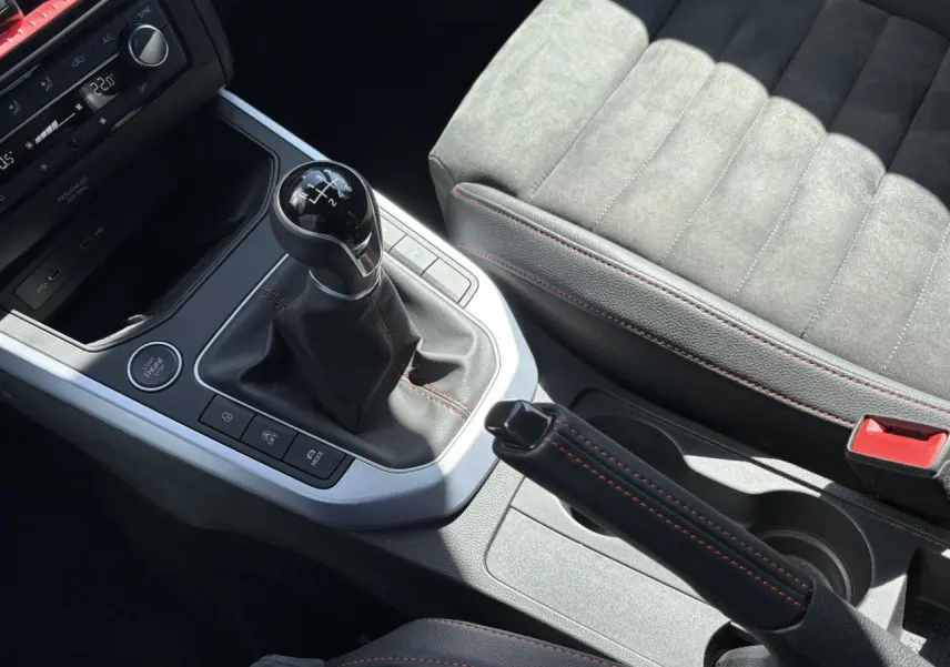 Gros plan sur la console centrale du SEAT Arona TSI 110 FR 2024, avec levier de vitesse manuel et sellerie suédine grise.