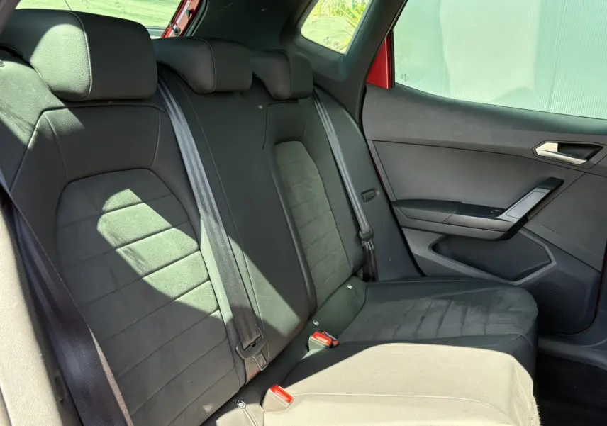 Vue latérale droite de la banquette arrière noire en suédine du SEAT Arona Rouge Désir avec ceinture et porte intérieur visible.