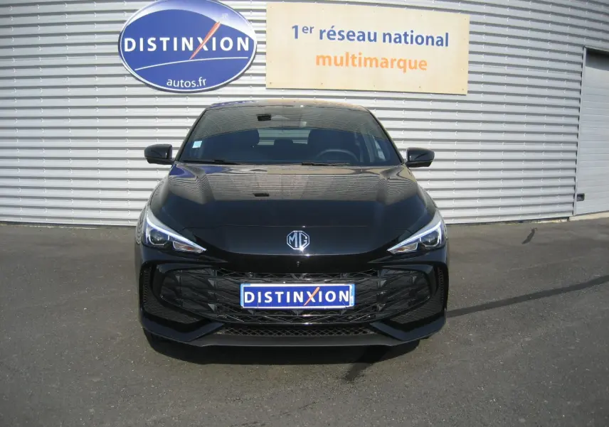 Vue frontale d'une MG3 1.5 HYBRID+ 195 CH LUXURY noire, avec calandre large et phares LED fins, sur parking extérieur.