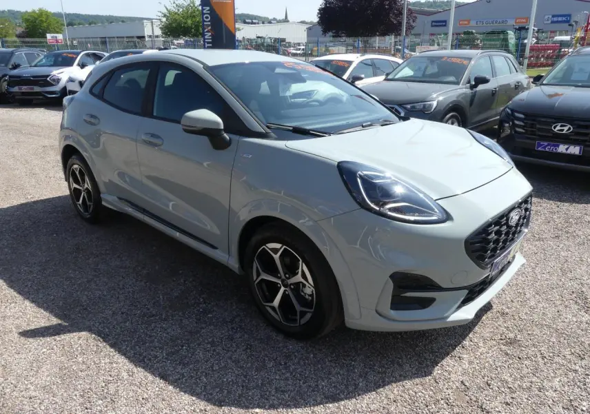 Ford Puma 2025 gris métallisé en vue 3/4 avant droit, avec jantes alliage et calandre noire sportive.