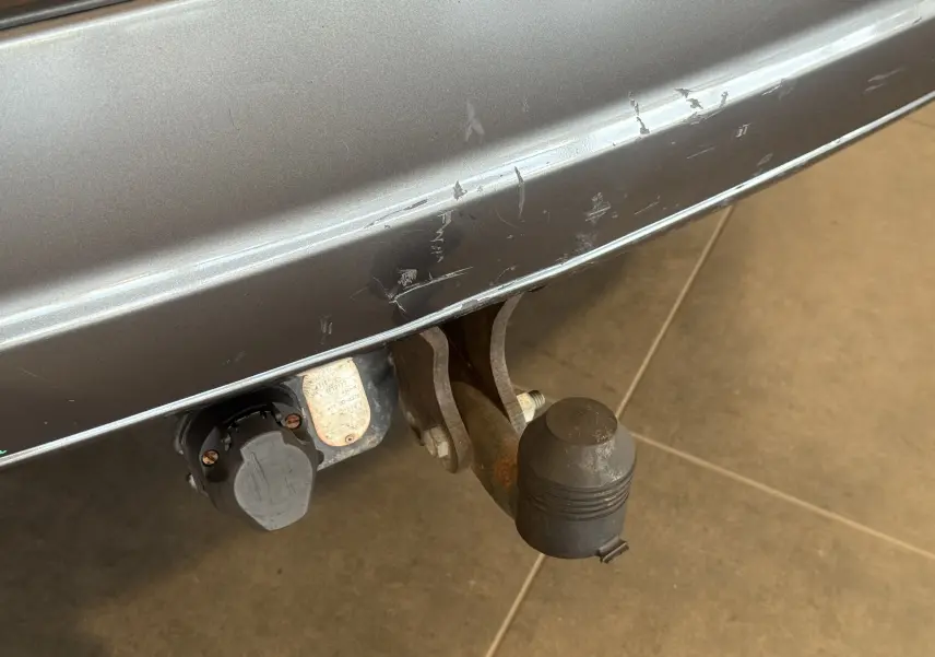 Gros plan sur l'attelage d'une KIA Sorento gris 2005, montrant le crochet de remorquage et la prise électrique arrière.