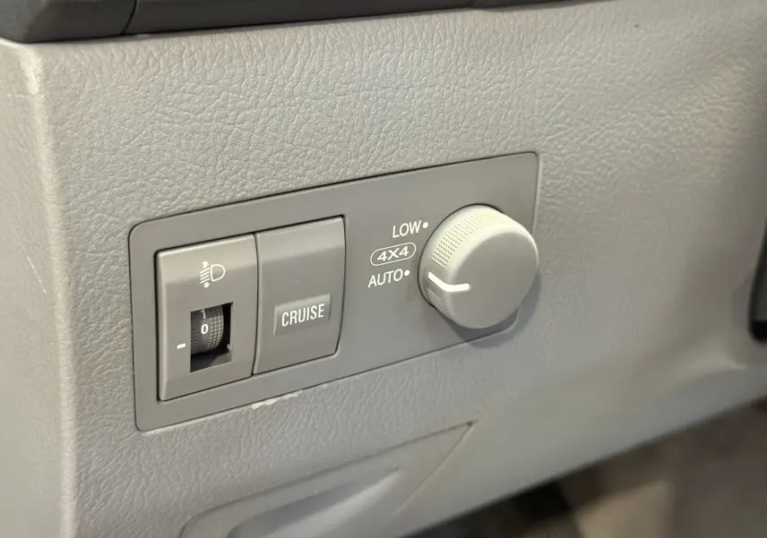 Gros plan sur les commandes 4x4 et régulateur de vitesse du tableau de bord gris du KIA Sorento 2005.