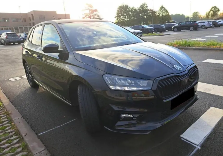 Vue 3/4 avant gauche d'une SKODA FABIA TSI 115 DSG Monte Carlo en Noir Magic avec calandre noire et phares LED allumés.