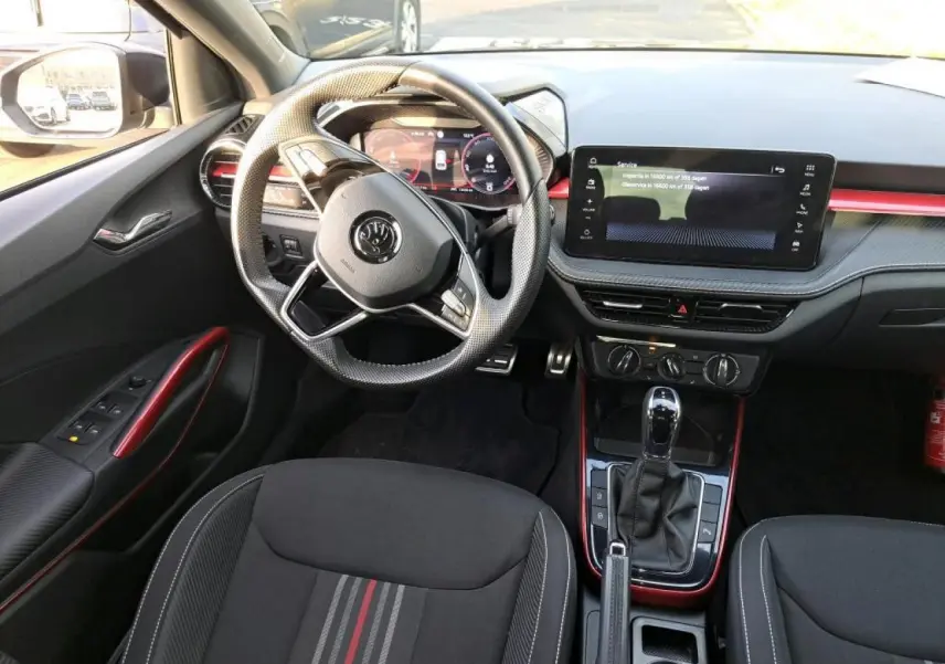 Vue intérieure côté conducteur de la Skoda Fabia Monte Carlo 2024 avec volant sport cuir et inserts rouges décoratifs.