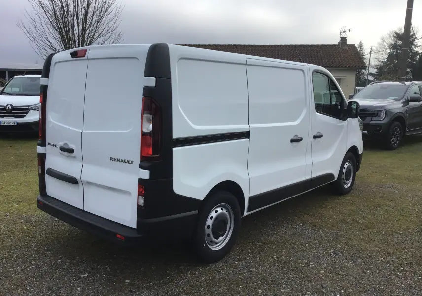 Vue 3/4 arrière droite du Renault Trafic Fourgon blanc 2025 avec portes arrière battantes et protections noires.