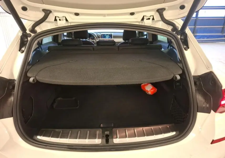 Coffre ouvert vu de l'arrière d'un BMW X2 blanc 2022, avec cache-bagages et intérieur noir visible.
