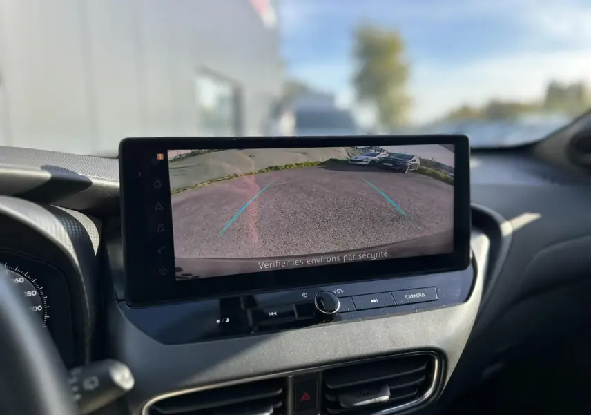 Vue intérieure centrée sur l'écran tactile affichant la caméra de recul du Nissan Juke noir 2025 avec tableau de bord moderne.