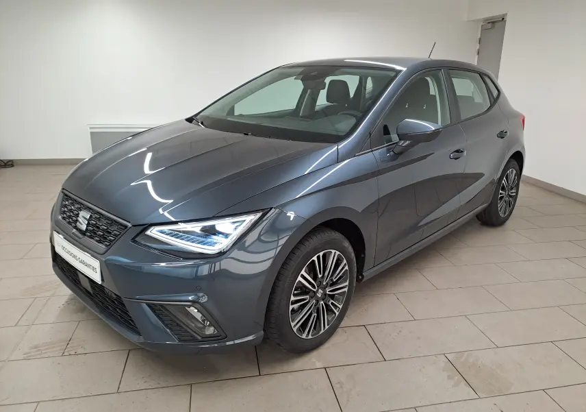 SEAT Ibiza 2025 gris magnétique en 3/4 avant droit, feux LED allumés et jantes alliage distinctives.