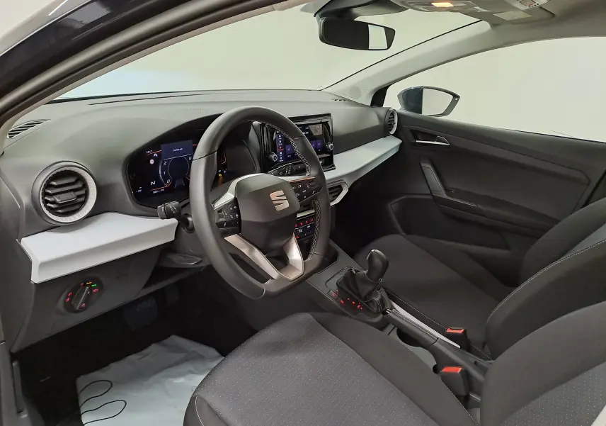 Vue intérieure côté conducteur de la SEAT Ibiza 2025 avec tableau de bord noir et blanc et volant multifonction.