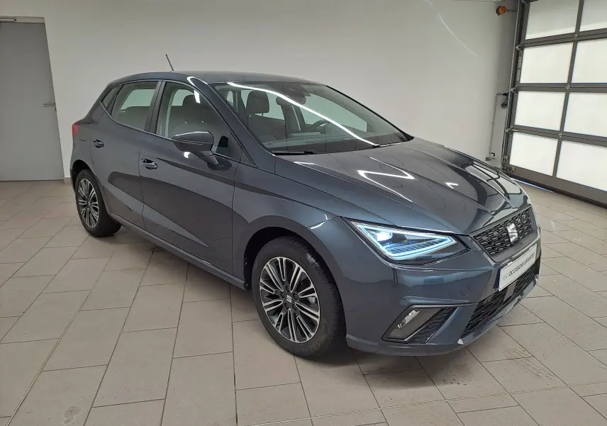 SEAT Ibiza 1.0 TSI 115 DSG7 Copa gris magnétique vue 3/4 avant avec phares LED allumés en intérieur.