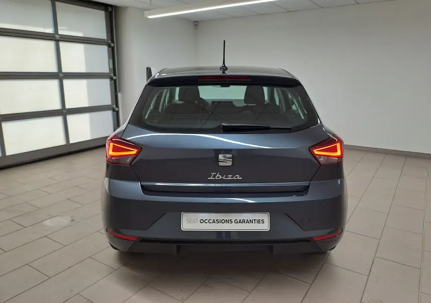 Vue arrière d'une SEAT Ibiza 2025 gris magnétique avec feux LED allumés dans un garage lumineux.