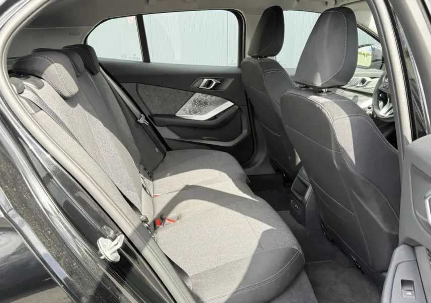 Vue intérieure côté gauche des sièges arrière en tissu anthracite d'une BMW Série 1 118dA Saphirschwarz avec port USB et garnitures modernes.
