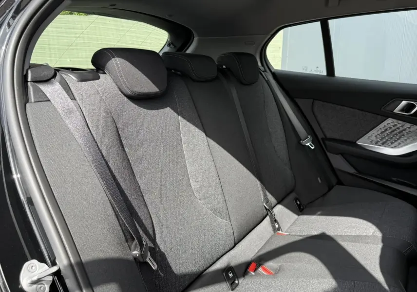 Vue latérale intérieure montrant la banquette arrière en tissu anthracite de la BMW Série 1 F70 noire.