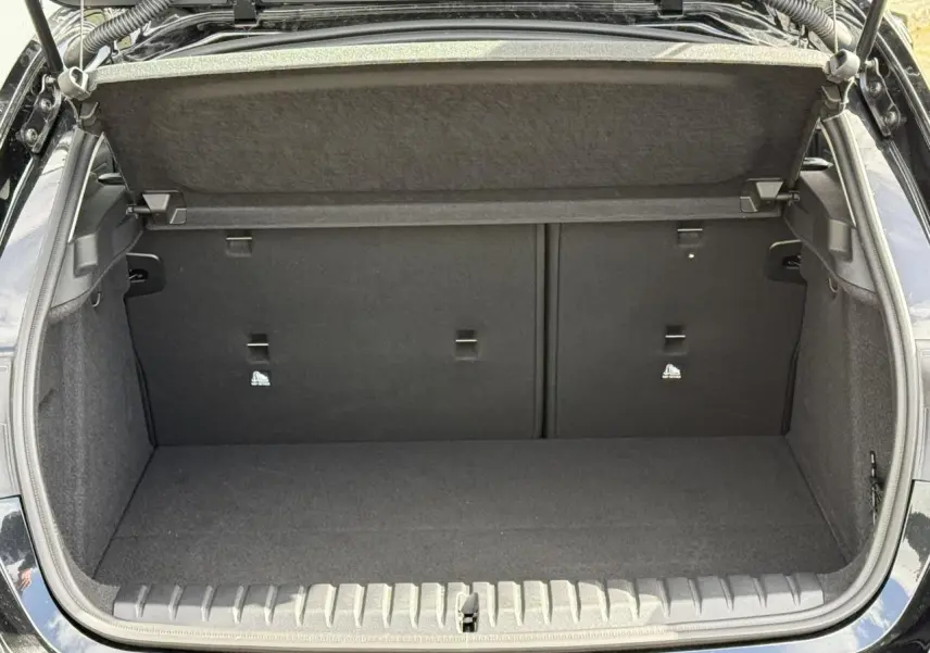 Coffre ouvert vu de l'arrière d'une BMW Série 1 F70 118dA M Sport en noir Saphirschwarz, intérieur tissu anthracite.