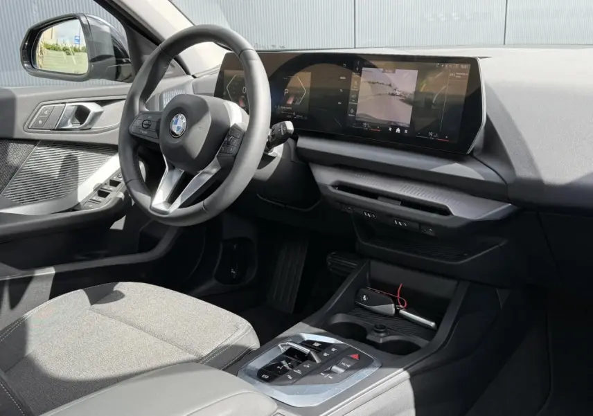 Vue intérieure côté conducteur de la BMW Série 1 118d M Sport 2025, tableau de bord moderne et sellerie tissu anthracite.
