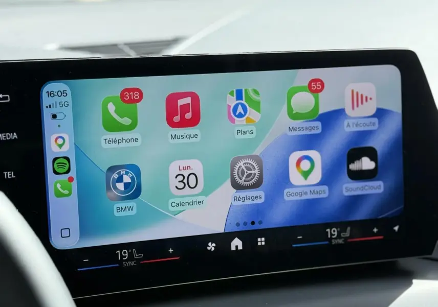 Écran tactile BMW Curved Display avec interface Apple CarPlay, affichage clair du tableau de bord intérieur.