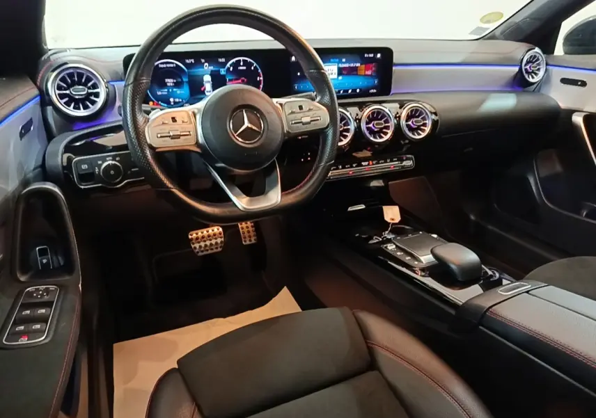 Vue intérieure avant du Mercedes CLA 200 d AMG Line 2022, tableau de bord numérique et volant cuir noir avec surpiqûres rouges.