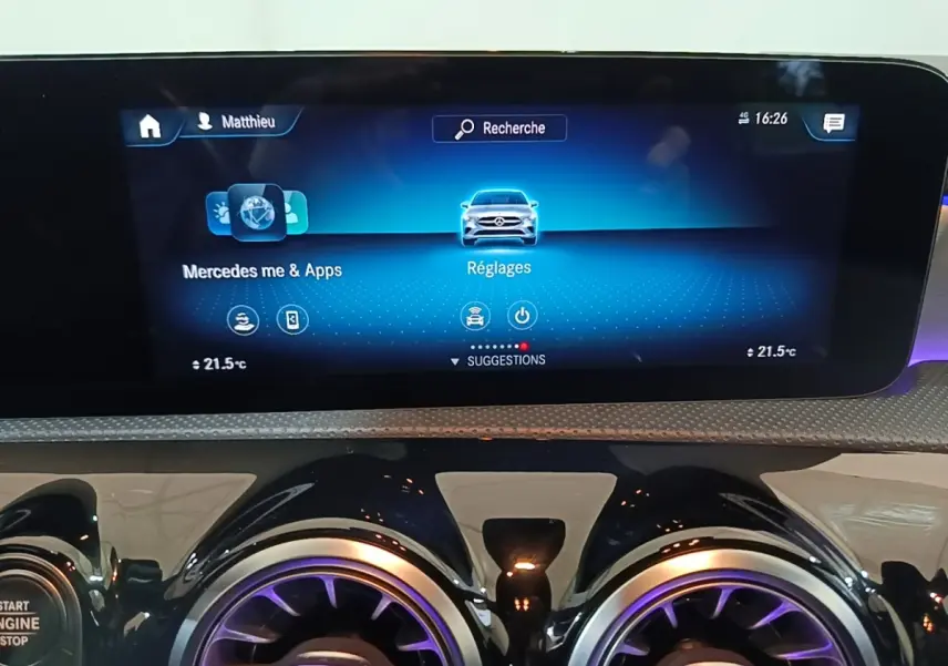 Écran tactile central et aérateurs ronds avec éclairage violet dans le tableau de bord d'une Mercedes CLA 200 d AMG Line noire.