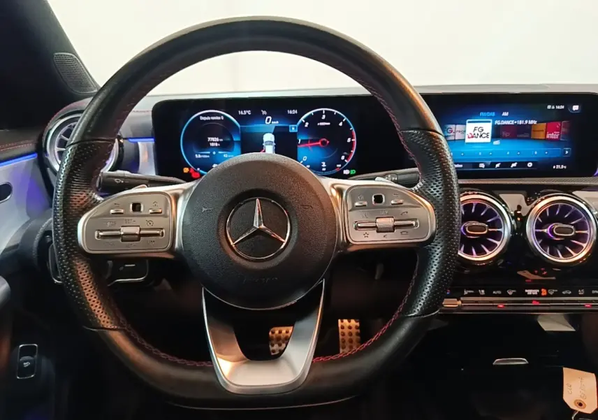 Vue frontale du volant cuir noir perforé et du tableau de bord numérique éclairé d'une Mercedes CLA 200 d AMG Line 2022.