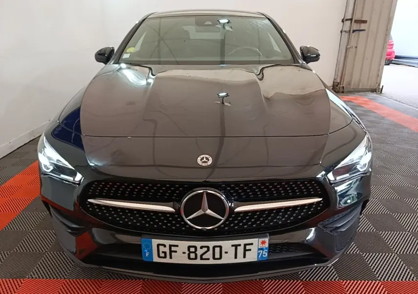 Vue de face d'une Mercedes CLA 200 d AMG Line noire avec calandre étoilée et phares LED allumés.