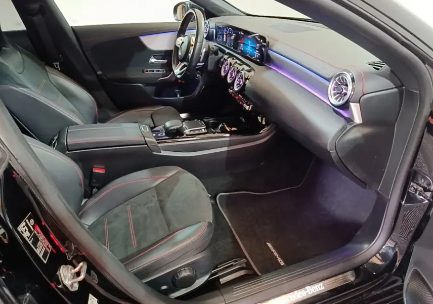 Vue intérieure côté passager avant de la Mercedes CLA 200 d AMG Line noire avec éclairage d'ambiance violet et finitions sport.