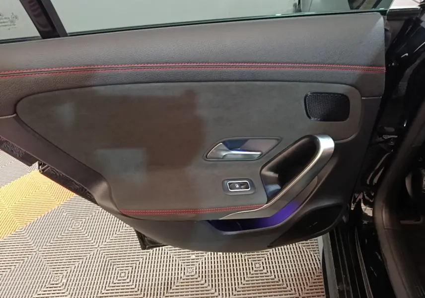 Gros plan sur la porte intérieure côté gauche noire avec surpiqûres rouges et poignée alu d'une Mercedes CLA 200 d AMG Line 2022.
