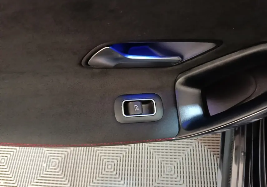 Détail de la poignée intérieure et bouton de verrouillage sur la porte côté gauche d'une Mercedes CLA 200 d AMG Line noire.