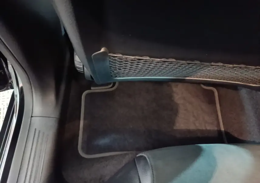 Vue intérieure du plancher côté passager arrière d'une Mercedes CLA 200 d AMG Line noire, avec filet de rangement sous siège.
